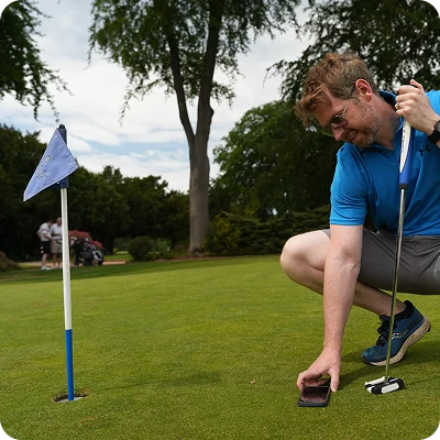 A golfer taking a reading beside the flag