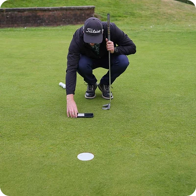 A golfer crouching to read the line of a putt